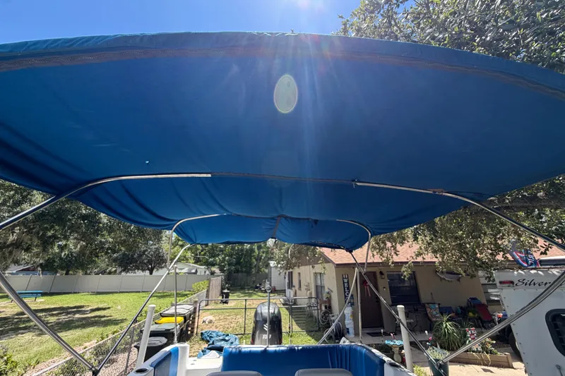 Slide: The Image of Un toldo Bimini azul en un barco en un patio, rodeado de árboles y edificios. - 14