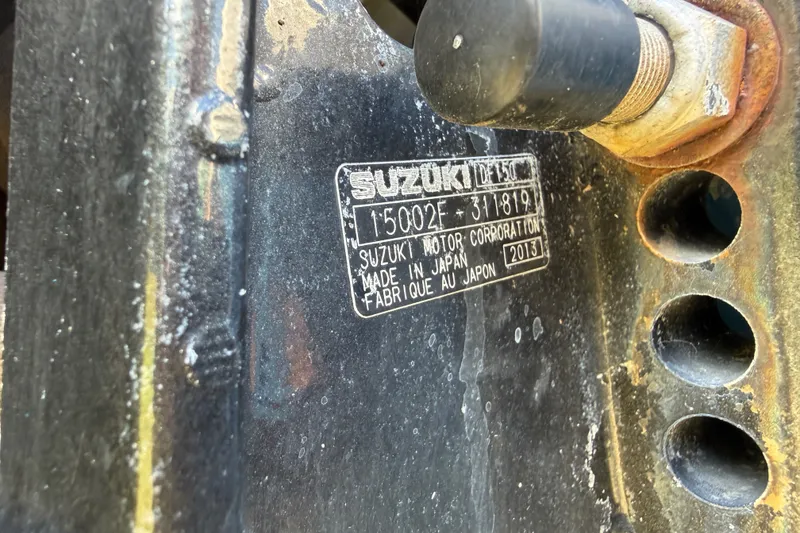 Slide: The Image of Primer plano de una pieza de motor Suzuki con número de serie y detalles de fabricación. - 19