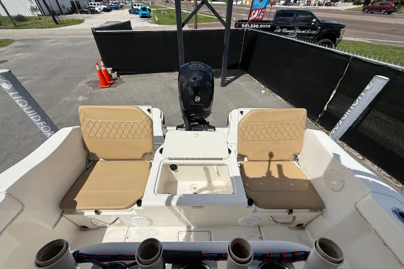 Slide: The Image of 2024 Bayliner Trophy T22CC boat interior with tan seating and motor view. - 58