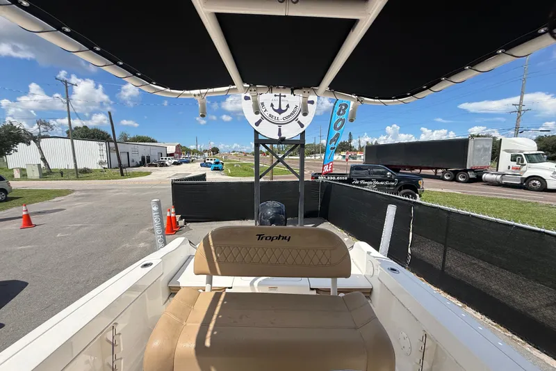 Slide: The Image of 2024 Bayliner Trophy T22CC boat interior with seating, parked outdoors under a sunny sky. - 55