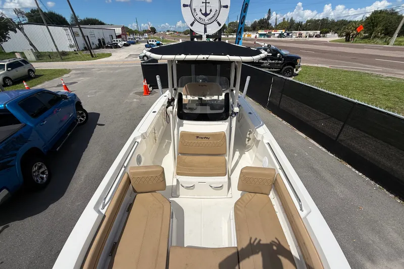 Slide: The Image of 2024 Bayliner Trophy T22CC boat with tan seating, parked outdoors on a sunny day. - 43