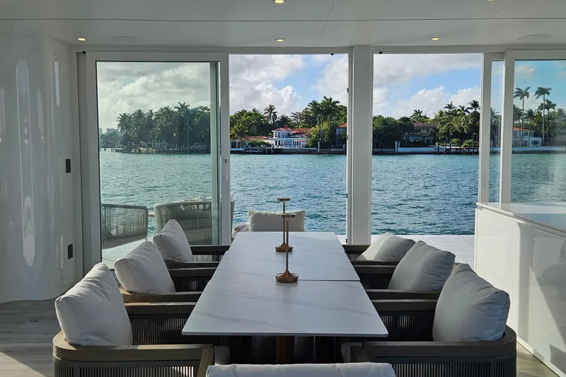 Slide: The Image of Luxurious Arkhaus Villa 50 interior with waterfront view, featuring elegant dining setup, 2025 model. - 2