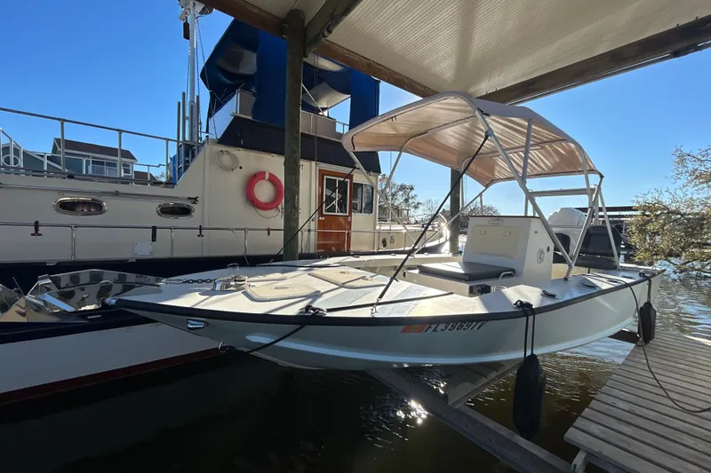 The Image of 2024 Custom Florida Flats CC boat docked under a canopy, with nearby vessels. - 0