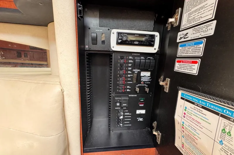 Slide: The Image of Electrical panel inside 2005 Sea Ray 300 Sundancer boat, featuring controls and safety notices. - 73
