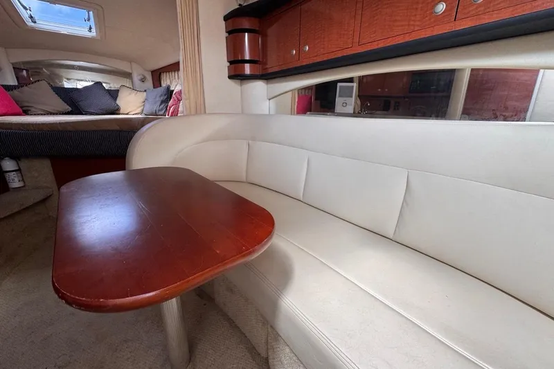 Slide: The Image of Interior of 2005 Sea Ray 300 Sundancer with white seating and wooden table. - 84