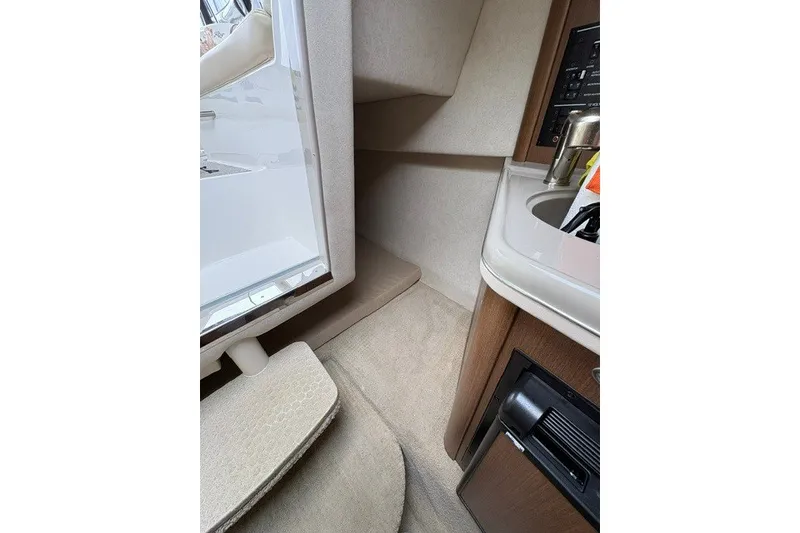Slide: The Image of Interior cabin of 2013 Sea Ray 240 Sundancer, featuring compact kitchenette and seating area. - 14