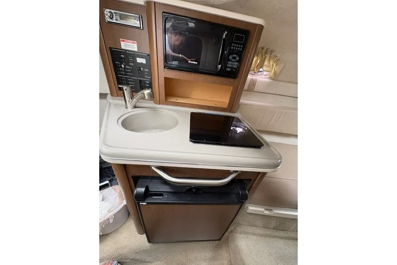 Slide: The Image of Compact kitchenette in 2013 Sea Ray 240 Sundancer with sink, microwave, and mini-fridge. - 15