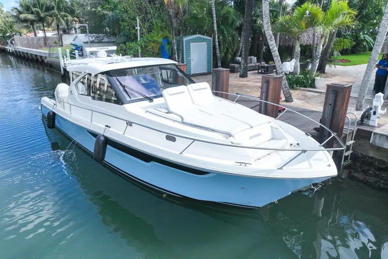 Slide: The Image of 2024 Pursuit OS 445 Offshore yacht docked in a tropical marina setting. - 1
