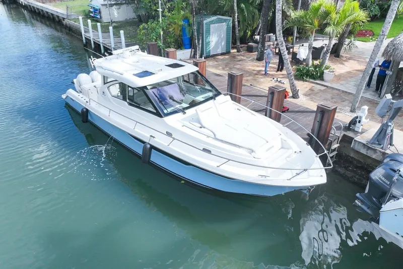 Slide: The Image of 2024 Pursuit OS 445 Offshore boat docked in a scenic waterfront setting. - 6