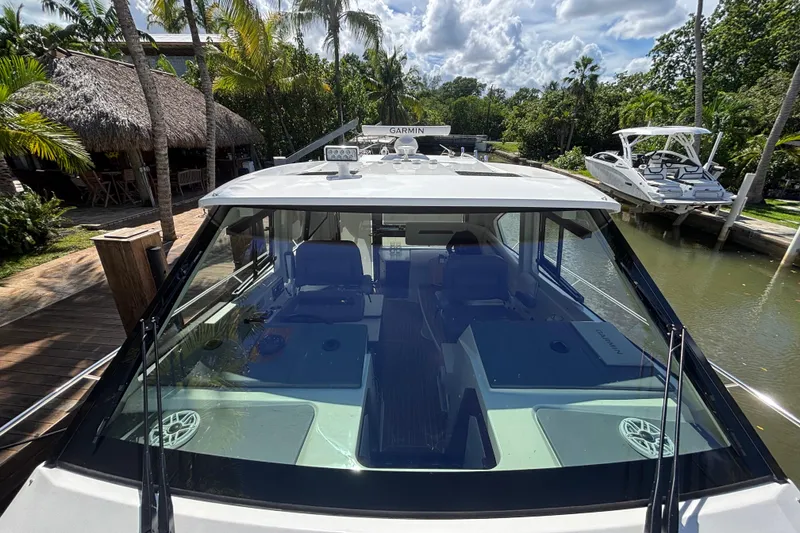 Slide: The Image of 2024 Pursuit OS 445 Offshore boat docked near tropical palm trees and waterfront. - 34