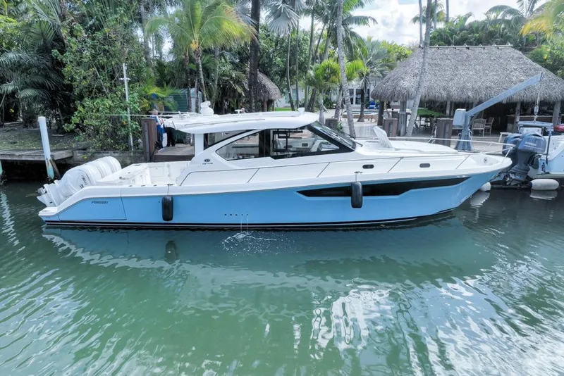 Slide: The Image of 2024 Pursuit OS 445 Offshore boat docked in tropical marina setting. - 4