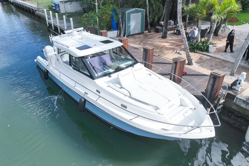 Slide: The Image of 2024 Pursuit OS 445 Offshore boat docked by a waterfront patio. - 7