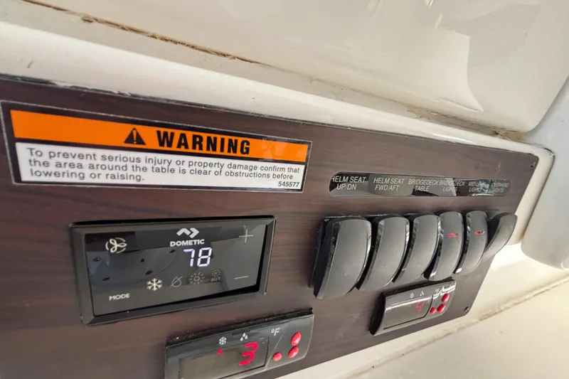 Slide: The Image of Control panel of 2024 Pursuit OS 445 Offshore with warning label and temperature display. - 98