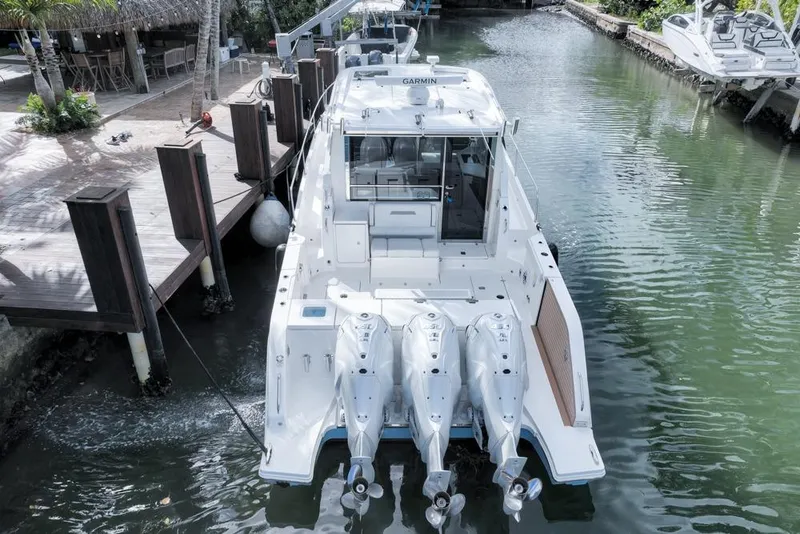 Slide: The Image of 2024 Pursuit OS 445 Offshore boat docked, featuring triple outboard engines. - 13