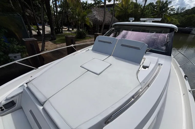 Slide: The Image of 2024 Pursuit OS 445 Offshore yacht with spacious sun deck, docked near tropical foliage. - 30
