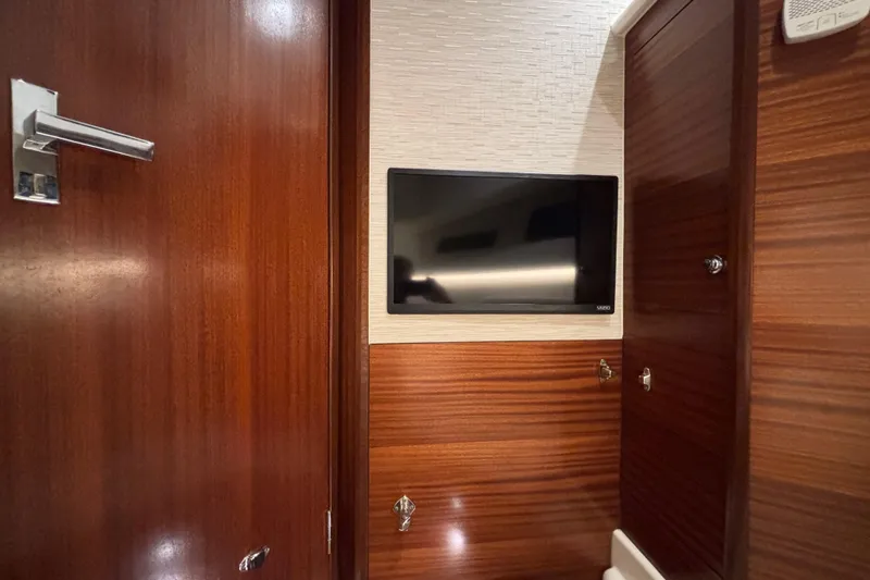 Slide: The Image of 2024 Pursuit OS 445 Offshore cabin interior with mounted TV and wooden finish. - 115