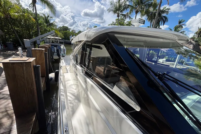 Slide: The Image of 2024 Pursuit OS 445 Offshore yacht docked, surrounded by tropical palm trees and clear skies. - 36
