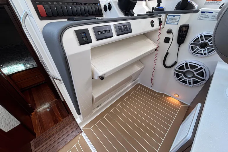 Slide: The Image of 2024 Pursuit OS 445 Offshore boat interior with control panel, speakers, and wooden flooring. - 88