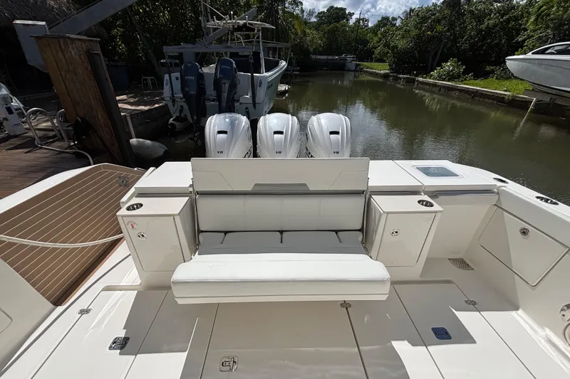 Slide: The Image of 2024 Pursuit OS 445 Offshore boat with triple V8 engines, docked in a serene canal. - 44