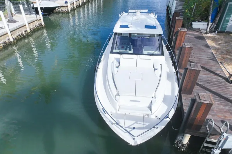 Slide: The Image of 2024 Pursuit OS 445 Offshore boat docked in a serene canal setting. - 15