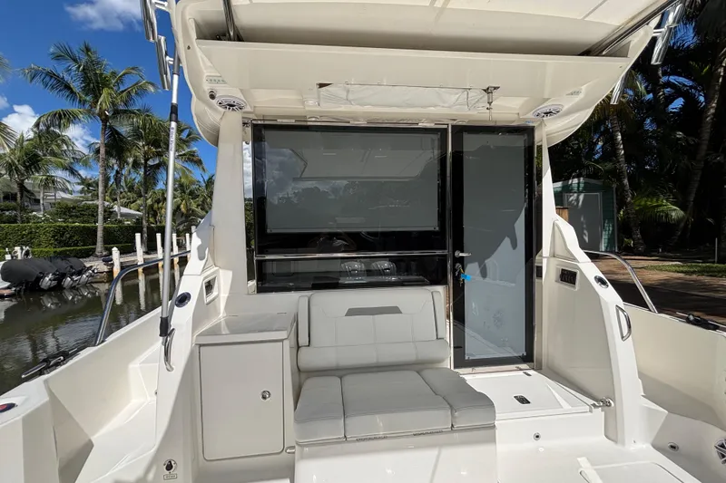 Slide: The Image of 2024 Pursuit OS 445 Offshore boat interior with seating, docked near palm trees. - 50