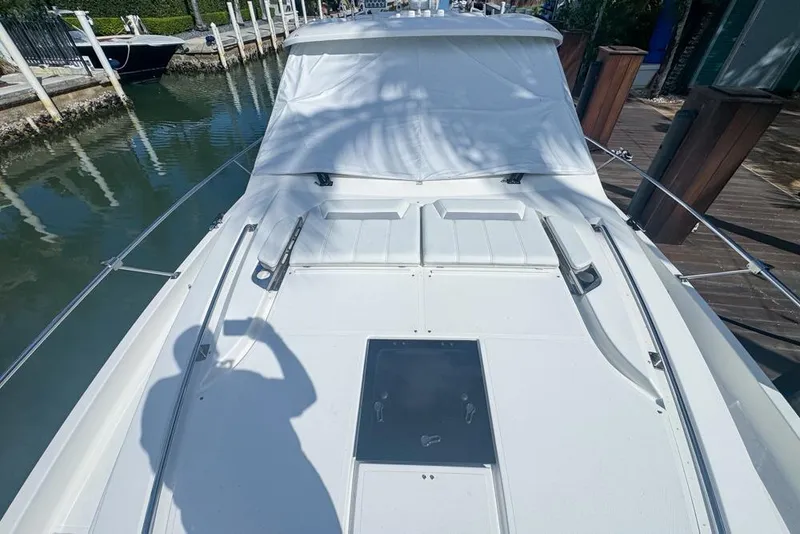 Slide: The Image of 2024 Pursuit OS 445 Offshore boat deck with white cover, docked in a marina. - 19