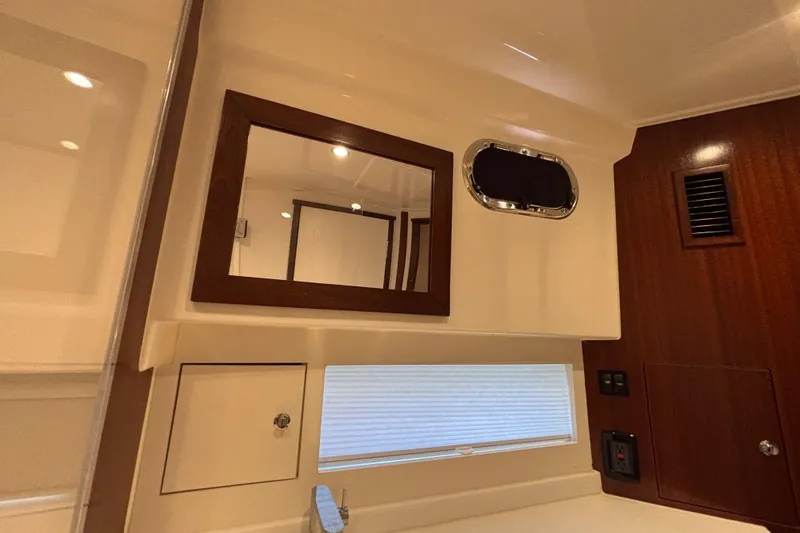 Slide: The Image of 2024 Pursuit OS 445 Offshore interior with mirror, porthole, and wood accents. - 108