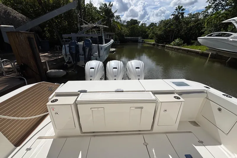 Slide: The Image of 2024 Pursuit OS 445 Offshore boat with triple outboard engines docked in a serene canal. - 43
