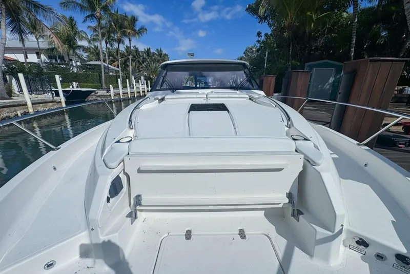Slide: The Image of 2024 Pursuit OS 445 Offshore boat docked, surrounded by palm trees and clear blue sky. - 24