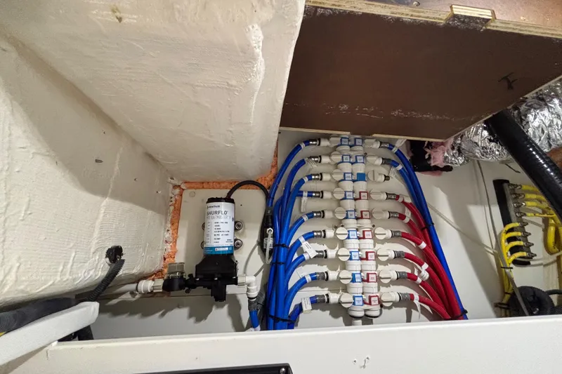 Slide: The Image of 2024 Pursuit OS 445 Offshore plumbing system with Shurflo pump and color-coded pipes. - 120