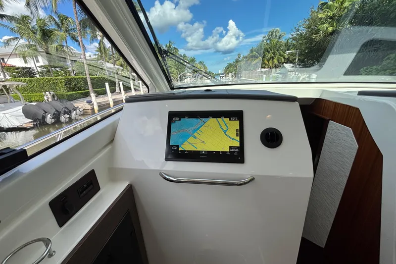 Slide: The Image of 2024 Pursuit OS 445 Offshore helm with navigation display, docked near palm trees. - 92