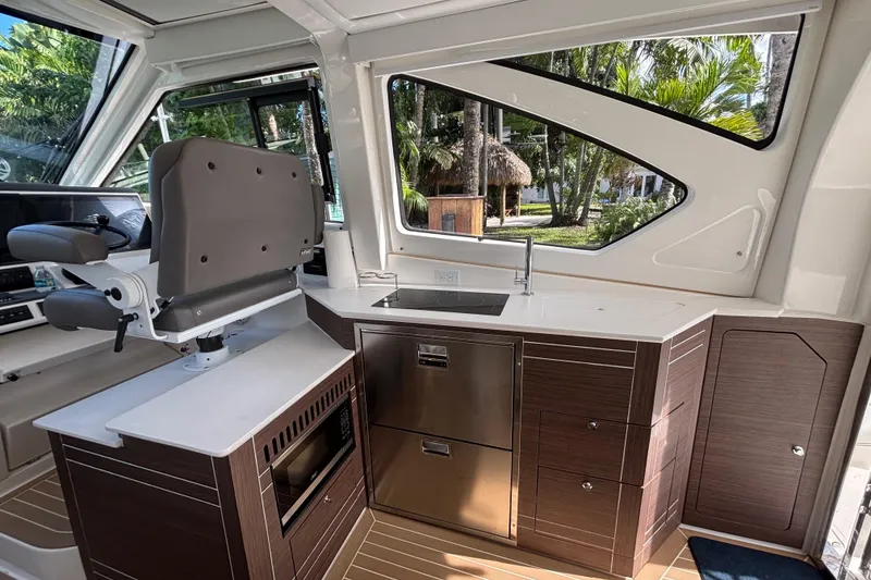 Slide: The Image of 2024 Pursuit OS 445 Offshore interior with helm seat, kitchenette, and modern cabinetry. - 65