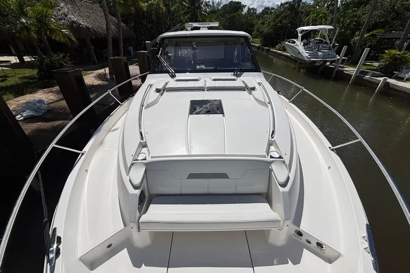 Slide: The Image of 2024 Pursuit OS 445 Offshore boat docked in a scenic canal setting. - 25