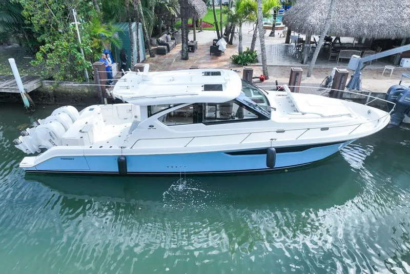 Slide: The Image of 2024 Pursuit OS 445 Offshore boat docked in a tropical marina setting. - 2
