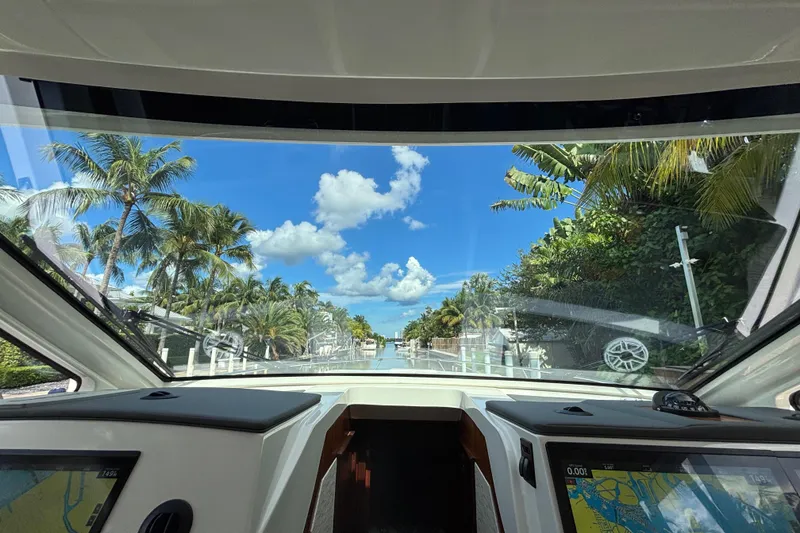 Slide: The Image of 2024 Pursuit OS 445 Offshore boat interior view with tropical palm trees and blue sky. - 89