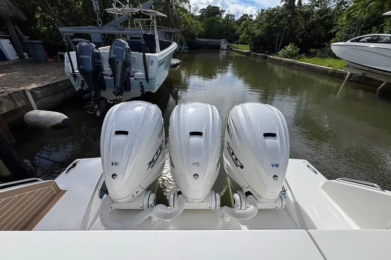 Slide: The Image of 2024 Pursuit OS 445 Offshore with triple V8 outboard engines docked in a serene canal. - 60