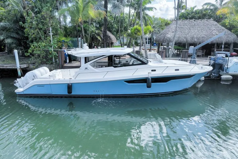 Slide: The Image of 2024 Pursuit OS 445 Offshore boat docked in tropical marina setting. - 3