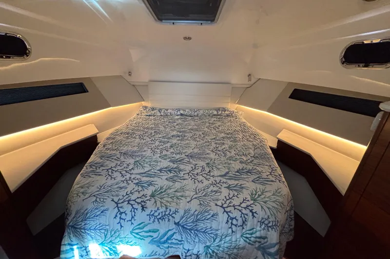 Slide: The Image of 2024 Pursuit OS 445 Offshore cabin with a cozy bed and ambient lighting. - 101