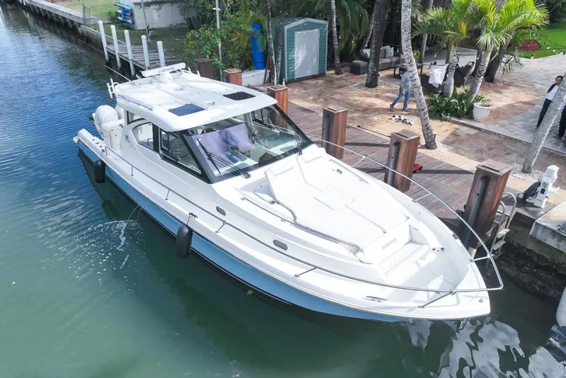 Slide: The Image of 2024 Pursuit OS 445 Offshore boat docked in a scenic waterfront setting. - 5