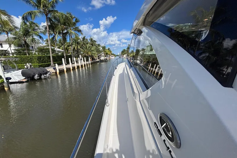 Slide: The Image of 2024 Pursuit OS 445 Offshore yacht cruising along a scenic, palm-lined waterway. - 39