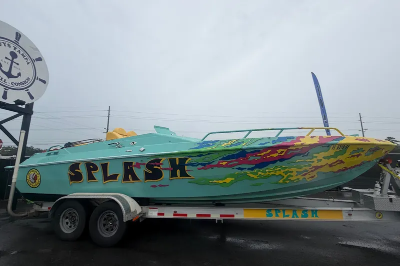 Slide: The Image of Colorful 2011 Apache 28 Splash speedboat on trailer, vibrant design, displayed outdoors. - 2