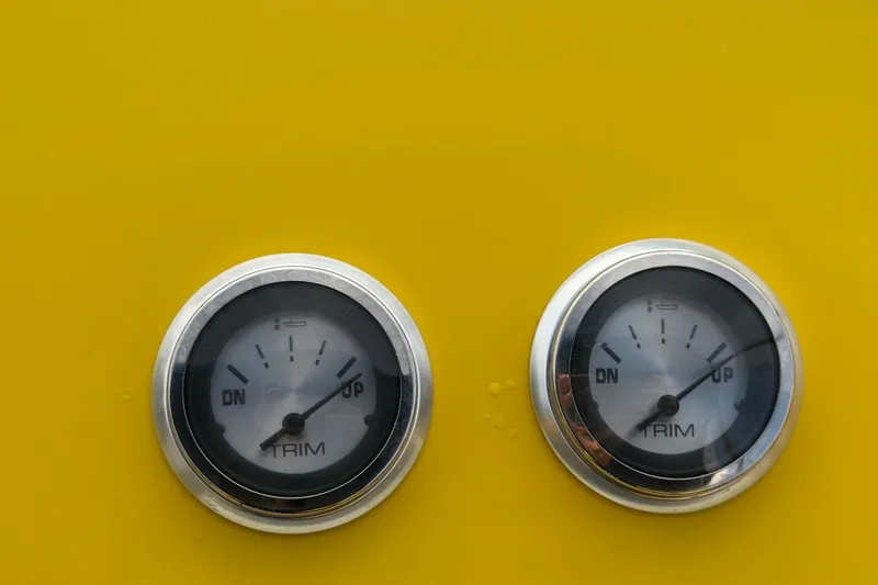 Slide: The Image of Close-up of two trim gauges on a yellow 2011 Apache 28 Splash boat. - 32