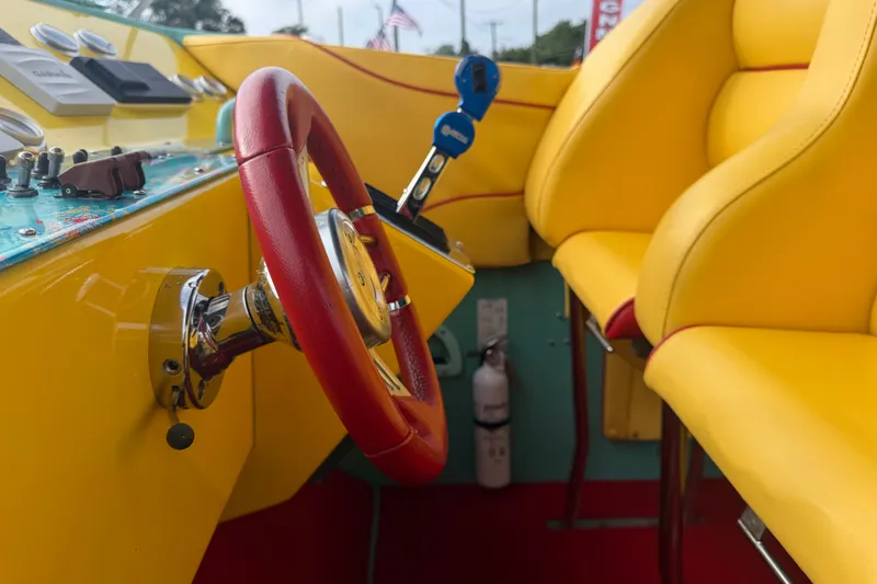 Slide: The Image of Interior of 2011 Apache 28 Splash boat with vibrant yellow seats and red steering wheel. - 37