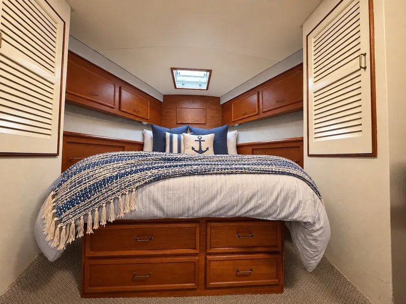 Slide: The Image of A cozy yacht bedroom with a large bed, blue pillows, and wooden cabinetry. - 48