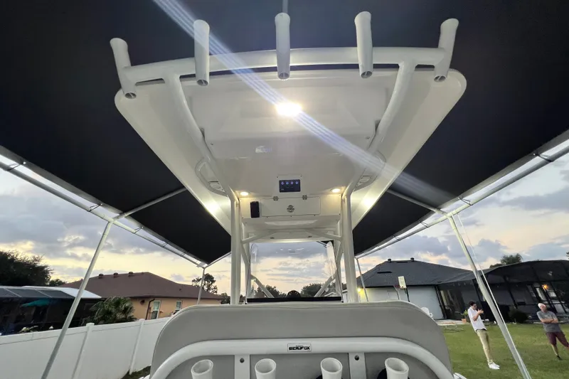Slide: The Image of 2024 Sea Fox 228 Commander boat interior with rod holders and canopy, under evening sky. - 15