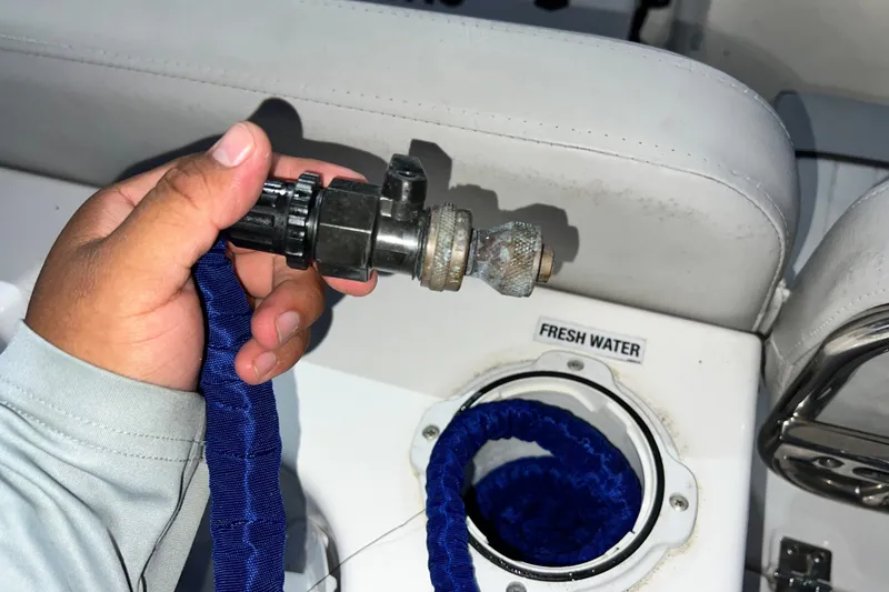 Slide: The Image of Hand holding a hose connector near a fresh water inlet on a 2024 Sea Fox 228 Commander boat. - 68
