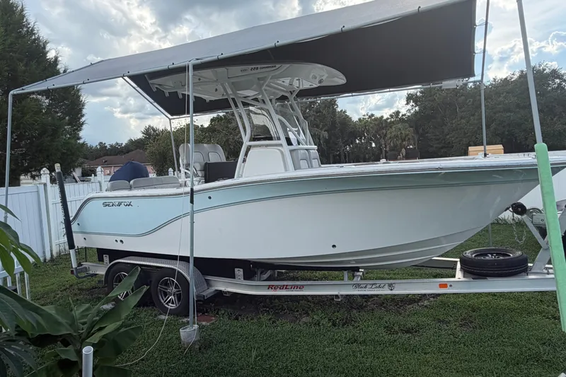 The Image of 2024 Sea Fox 228 Commander boat on trailer under canopy, parked in grassy yard. - 0