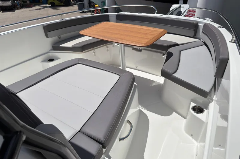 Slide: The Image of 2022 Jeanneau Leader 9.0 CC boat interior with cushioned seating and wooden table. - 29