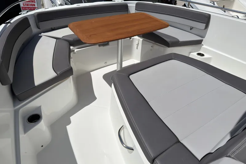 Slide: The Image of 2022 Jeanneau Leader 9.0 CC boat interior with cushioned seating and wooden table. - 24