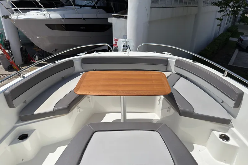 Slide: The Image of 2022 Jeanneau Leader 9.0 CC boat interior with cushioned seating and wooden table. - 25